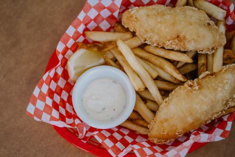 Fried fish and fries in basket with red liner