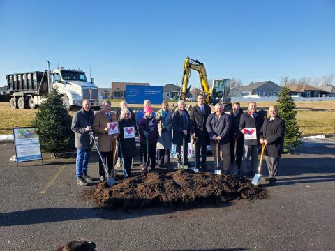 Group of people holding shovels in front of sod pile